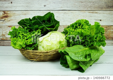 Fresh raw Iceberg, Romaine and Green Cos lettuces in bamboo basket on wooden background Fresh raw Iceberg, Romaine and Green Cos lettuces in bamboo basket on wooden background 140986772