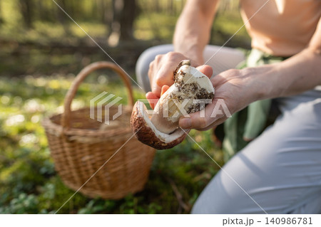 Woman picks mushroom in forest, cleaning, scrapes dirt off porcini with knife. Foraging wild food. 140986781