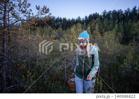 Focused woman with headlamp foraging mushrooms in cold autumn forest at twilight, North solo travel Focused woman with headlamp foraging mushrooms in cold autumn forest at twilight, North solo travel 140986822