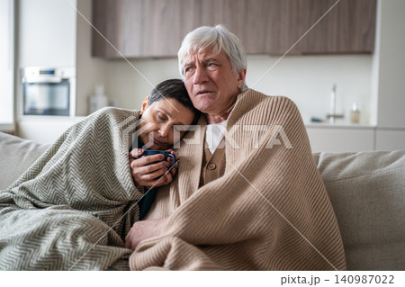 Senior family man and woman sharing cold flu sickness, sitting together on sofa suffering from fever Senior family man and woman sharing cold flu sickness, sitting together on sofa suffering from fever 140987022