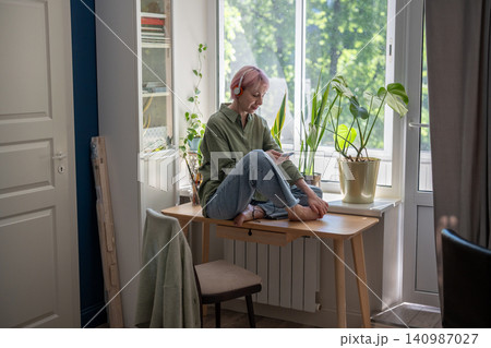 Happy mature woman in headphones scrolling music playlist on online audio digital streaming service. Happy mature woman in headphones scrolling music playlist on online audio digital streaming service. 140987027