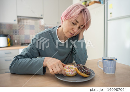 Stressed upset mature woman sugar addict feels guilty about weak mental state eats junk food snacks. 140987064