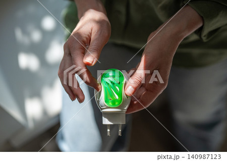 Woman inserting chemical anti insects plate in electrical mosquito fumigator device for home safety 140987123