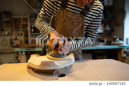 Sanding wood with orbital sander at workshop. Carpentry workshop. Furniture production Sanding wood with orbital sander at workshop. Carpentry workshop. Furniture production 140987185