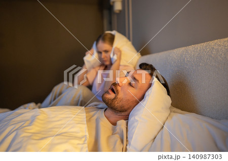 Exhausted female with sleep deprivation and insomnia suffering from partner snoring at night. 140987303