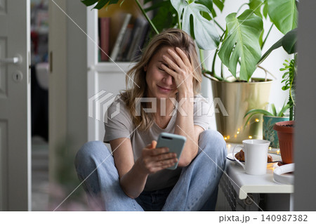 Confused woman doing facepalm gesture, looking at mobile phone, sent email to the wrong address 140987382