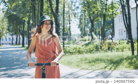 Energetic teenager gliding on electric scooter, navigating green summer park with youthful freedom and sunlit enthusiasm Energetic teenager gliding on electric scooter, navigating green summer park with youthful freedom and sunlit enthusiasm 140987500