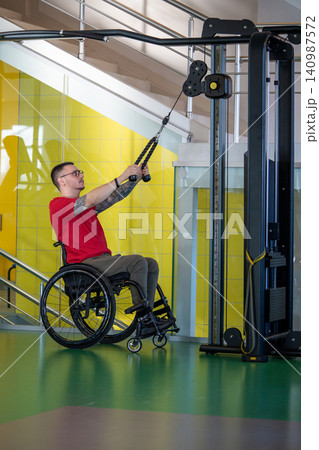 Motivated strong disabled man training upper body muscles with sports training machine for therapy Motivated strong disabled man training upper body muscles with sports training machine for therapy 140987572