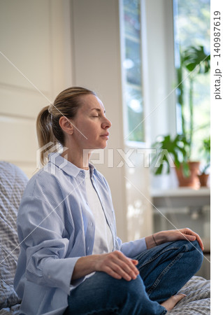 Serene mature woman practicing deep breathing and mindfulness exercises for mental clarity. Serene mature woman practicing deep breathing and mindfulness exercises for mental clarity. 140987619