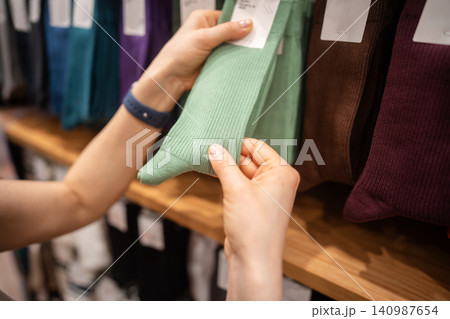 Female customer shopping in fashion clothing store, picking pair of socks on hanger display. Female customer shopping in fashion clothing store, picking pair of socks on hanger display. 140987654