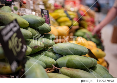 Various assortment of exotic tropical fruits at supermarket in Thailand, customer choosing mangos. 140987658