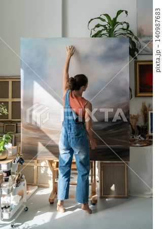 Inspired female artist painter creating abstract paintings at home studio, working with canvas. Inspired female artist painter creating abstract paintings at home studio, working with canvas. 140987683