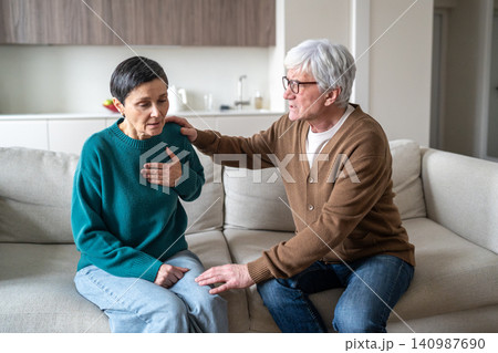 Worried husband embracing senior wife with sudden chest pain, showing emotional support and care. Worried husband embracing senior wife with sudden chest pain, showing emotional support and care. 140987690