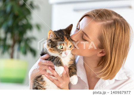 Smiling woman in kissing and hugging with tenderness and love cat, holding in arms Smiling woman in kissing and hugging with tenderness and love cat, holding in arms 140987977