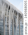 Icicles hang from roof and wall in winter. Frozen water from melting ice and snow during spring thaw 140988005