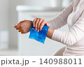 Woman applying cold compress to a her painful wrist 140988011