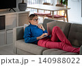 Young woman lying on comfortable sofa works on laptop and types information about business 140988022