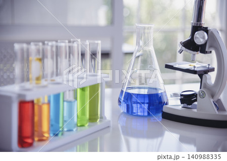 Science laboratory chemistry test science lab with microscope, glass tubes, chemical beaker white table scientific background. Colorful Liquid biology laboratory chemical fluid scientist experiment Science laboratory chemistry test science lab with microscope, glass tubes, chemical beaker white table scientific background. Colorful Liquid biology laboratory chemical fluid scientist experiment 140988335