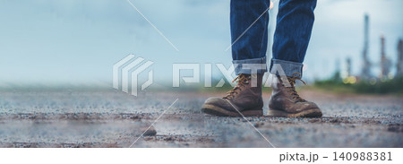 Men wear construction Boots safety footwear for worker at construction site. Engineer Wear Jeans Brown Boots Worker on Background of Refinery. Engineer safety industry fashion footwear walking outdoor Men wear construction Boots safety footwear for worker at construction site. Engineer Wear Jeans Brown Boots Worker on Background of Refinery. Engineer safety industry fashion footwear walking outdoor 140988381