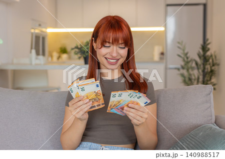 Young woman counts cash euros with smile happy about salary savings plans invest profit big growth Young woman counts cash euros with smile happy about salary savings plans invest profit big growth 140988517