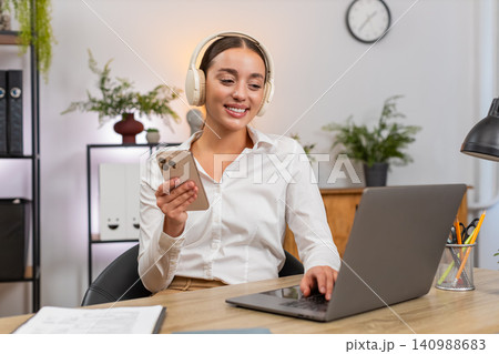 Young happy businesswoman plays soft music on smartphone relax chill taking a break returns to tasks Young happy businesswoman plays soft music on smartphone relax chill taking a break returns to tasks 140988683