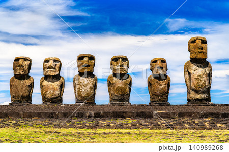 Row of ancient stone moai statues standing at Ahu Tongariki under a blue sky on Easter Island, Chile. Row of ancient stone moai statues standing at Ahu Tongariki under a blue sky on Easter Island, Chile. 140989268