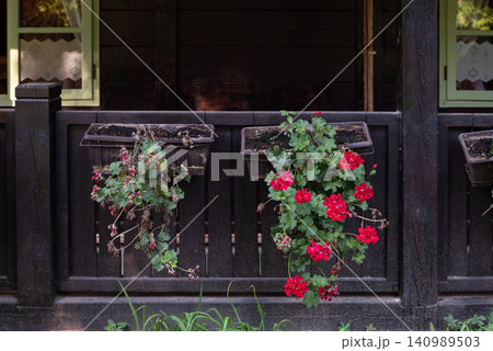 Rustic porch with red geranium flower boxes Rustic porch with red geranium flower boxes 140989503