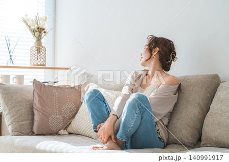 リビングのソファでリラックスするおしゃれな主婦のアジア人女性 リビングのソファでリラックスするおしゃれな主婦のアジア人女性 140991917
