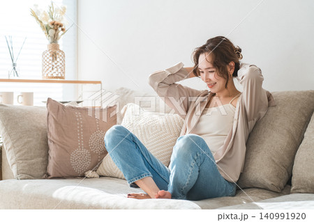 リビングのソファでリラックスするおしゃれな主婦のアジア人女性 リビングのソファでリラックスするおしゃれな主婦のアジア人女性 140991920