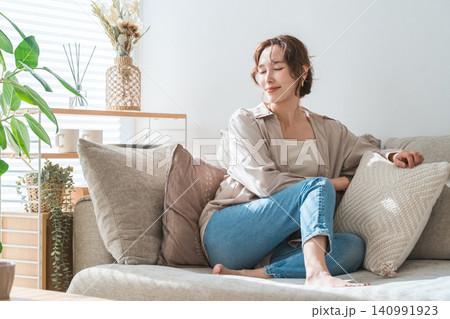 リビングのソファでリラックスするおしゃれな主婦のアジア人女性 リビングのソファでリラックスするおしゃれな主婦のアジア人女性 140991923