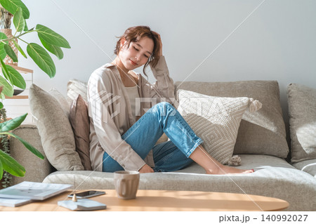 西陽の当たるリビングソファーに座る女性(モデル,ファッション,日差し) 西陽の当たるリビングソファーに座る女性(モデル,ファッション,日差し) 140992027