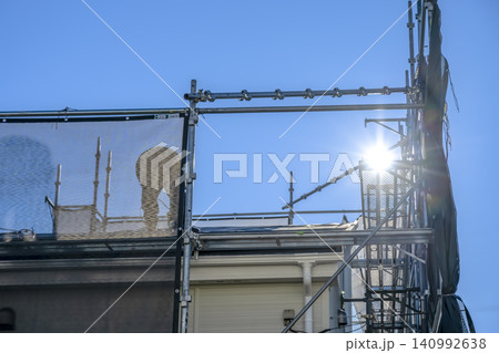 青空の下で屋根リフォーム作業をする職人と仮設足場 青空の下で屋根リフォーム作業をする職人と仮設足場 140992638