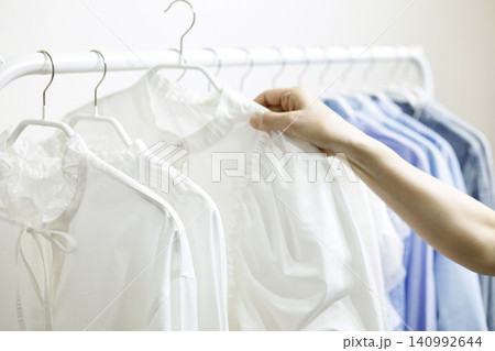 ラックにかかった服を手に取る女性の手元 ラックにかかった服を手に取る女性の手元 140992644