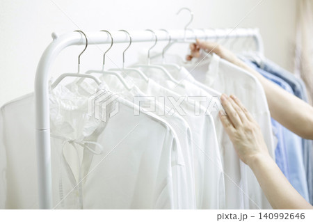 ラックにかかった服を手に取る女性の手元 ラックにかかった服を手に取る女性の手元 140992646
