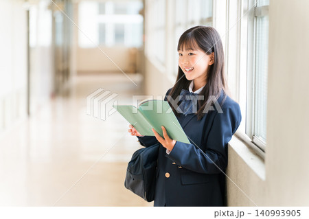 学校の廊下で本を持つ小学生,中学生,高校生の女子生徒 学校の廊下で本を持つ小学生,中学生,高校生の女子生徒 140993905