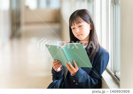 学校の廊下で本を持つ小学生,中学生,高校生の女子生徒 学校の廊下で本を持つ小学生,中学生,高校生の女子生徒 140993909