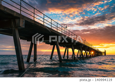 Coastal sunset at Glenelg Jetty with people silhouettes and sunbeams, South Australia 140994119