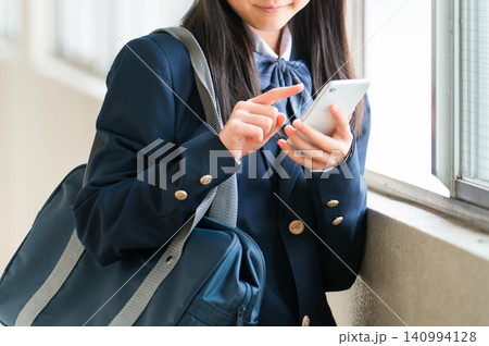 校舎の廊下でスマホを使う笑顔の高校生の女の子(フィルタリング,ネットリテラシー) 校舎の廊下でスマホを使う笑顔の高校生の女の子(フィルタリング,ネットリテラシー) 140994128