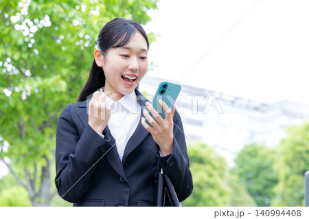 就活 リクルートスーツを着てスマホを見ている女性 就活 リクルートスーツを着てスマホを見ている女性 140994408