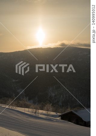 夕日に輝く雪庇となだらかな丘 140995012