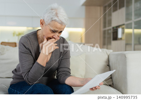 Sad tired ill sick lonely disappointed older senior woman reading bad news at home alone. Unhappy mature grandmother experiencing grief relative death. Stressed elder lady with paper document bill Sad tired ill sick lonely disappointed older senior woman reading bad news at home alone. Unhappy mature grandmother experiencing grief relative death. Stressed elder lady with paper document bill 140995735