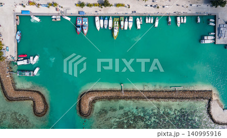 Aerial top view of Maafushi island jetty with tour boats parking inside the breakwaters Aerial top view of Maafushi island jetty with tour boats parking inside the breakwaters 140995916