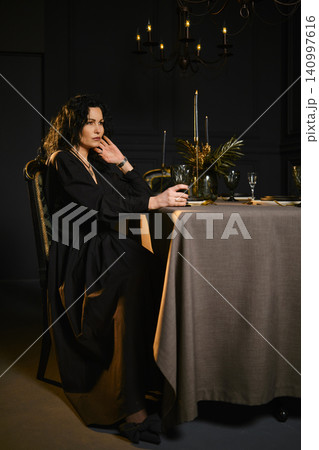 A woman sits at a table in a dimly lit room A woman sits at a table in a dimly lit room 140997616