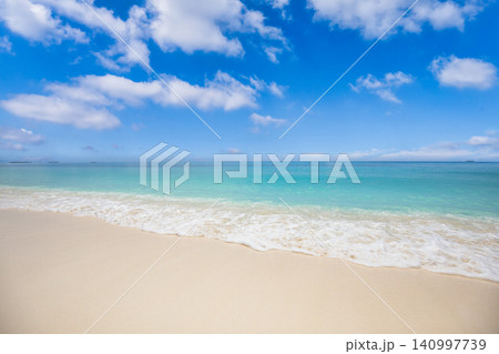 Calm turquoise sea meeting soft white sand shore. Bright blue sky over a tranquil tropical beach. Pristine paradise scene for background design copy space 140997739