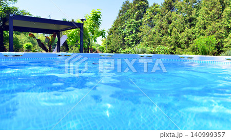 Outdoor swimming pool in a garden with plants and trees. Outdoor swimming pool in a garden with plants and trees. 140999357