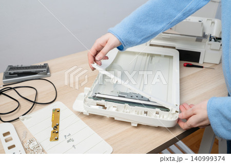 Hands Repairing Flatbed Scanner On Desk During Electronic Device Disassembly And Maintenance Hands Repairing Flatbed Scanner On Desk During Electronic Device Disassembly And Maintenance 140999374