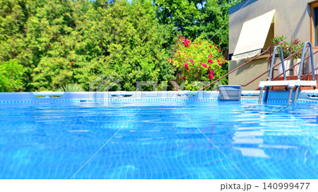 Large swimming pool set in the backyard next to the house. 140999477