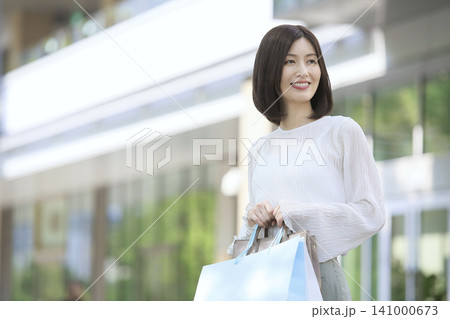 ショッピングバックを持って歩く30代女性 買い物イメージ 141000673