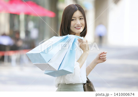 ショッピングバックを持って歩く30代女性 買い物イメージ ショッピングバックを持って歩く30代女性 買い物イメージ 141000674
