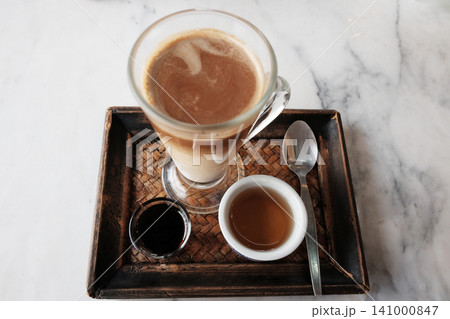 Top view of Iced latte coffee and hot black coffee with tea in a woven tray marble table Top view of Iced latte coffee and hot black coffee with tea in a woven tray marble table 141000847